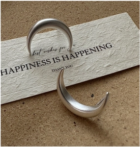 Detailed macro view of matte S925 sterling silver crescent earrings on a gift card