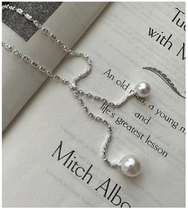 Close-up of S925 silver Y-shaped tassel necklace with elegant white pearls on a book