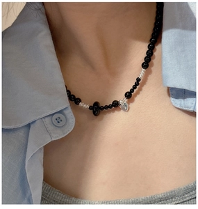 Detail of S925 silver black onyx beaded necklace with heart pendant on a model