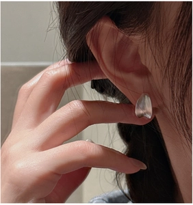 Close-up of minimalist matte silver C-shaped earring with a fluid petal-like design