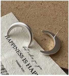 Detail of matte silver crescent earrings on card showing S925 hallmark and texture