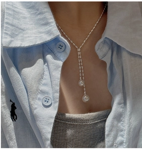 Detail showing elegant Y-shaped silver tassel necklace with white pearls on a model