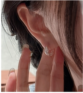 Macro shot of minimalist transparent resin hoop earring on ear with jelly-like texture