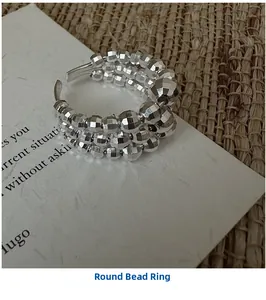 Macro detail of triple-layer silver beaded ring with faceted surface on white paper