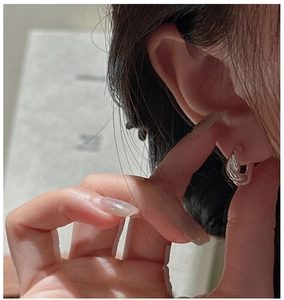 Close-up of S925 sterling silver twisted hoop earring worn on a model's ear