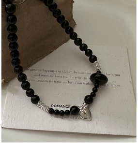 Detail of S925 silver heart pendant and black onyx beads necklace on a textured background