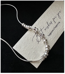 Macro shot of S925 silver necklace with textured cylinder pendants on snake chain