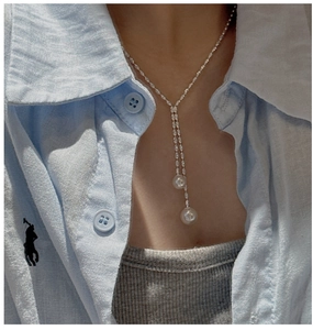Detail of S925 silver double layer pearl Y-pendant necklace on a model neckline