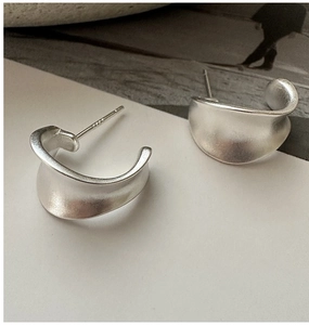 Detailed macro view of S925 sterling silver hallmark on matte C-shaped earrings