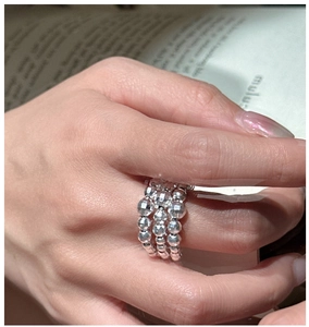 Detail of a three-layer beaded S925 sterling silver ring with faceted texture on finger