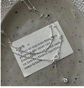 Macro shot of S925 sterling silver beaded chain with zircon pendant on a ceramic plate