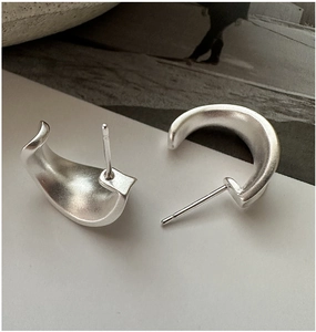 Detail view of 925 silver C-shape earrings with a minimalist matte finish and curved design