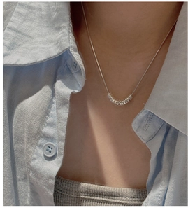 Minimalist S925 silver necklace with circular pendant on neck, worn over light blue shirt