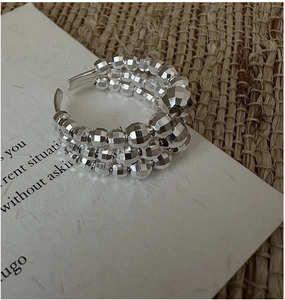 Macro shot of triple-layer faceted silver beaded ring on artistic card background