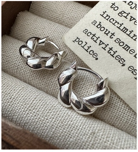 Macro shot of S925 sterling silver twisted hoop earrings in a wooden jewelry box