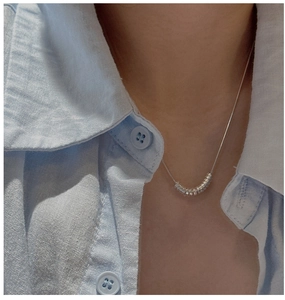 Close-up of minimalist S925 silver necklace with circular link pendant on blue fabric