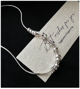 Detail of S925 sterling silver snake chain with hammered ring pendants on a gift card