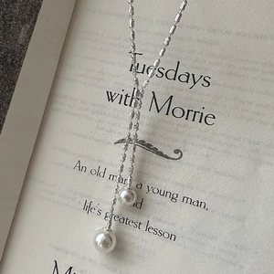 Elegant S925 sterling silver Y-shaped necklace with white pearl tassels on a book