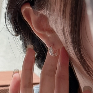 Minimalist S925 sterling silver twisted hoop earrings shown worn on an ear lobe