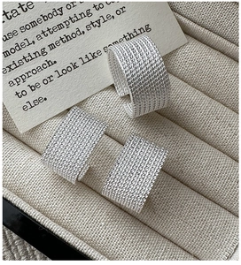 Macro shot of wide S925 sterling silver rings with textured woven pattern on jewelry tray