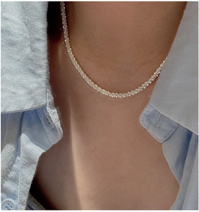 Detailed view of shimmering S925 sterling silver chain necklace on a model's neckline