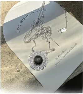 Macro shot of S925 silver necklace with textured round pendant and black obsidian stone