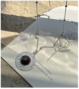 Macro detail of S925 silver hammered pendant necklace with obsidian stone on elegant card