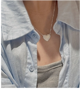 Close-up of 925 sterling silver heart necklace worn with casual linen shirt