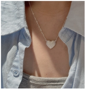 Detailed close-up of textured heart pendant necklace with shimmering silver finish