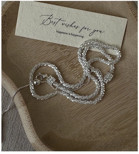 Close-up of sparkling S925 silver textured chain with lobster clasp on a wooden tray