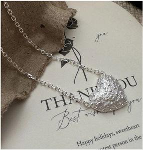 Macro shot of 925 silver heart necklace with embossed texture on an artistic background