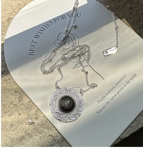 Detail of silver necklace featuring a hammered texture pendant with a black obsidian stone