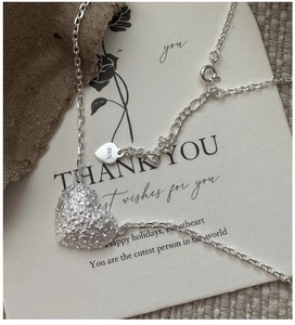 Detail of S925 sterling silver heart pendant with textured relief on vintage card