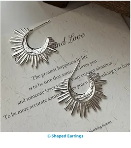 Macro detail of silver C-shaped fan earrings with textured solar ray pattern