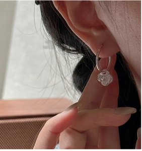 Détail de la boucle d'oreille fleur de camélia argentée sur l'oreille du mannequin