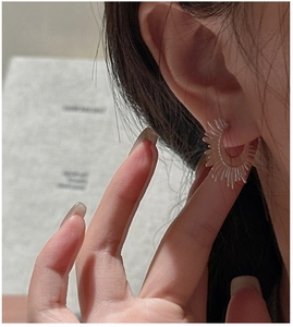 Macro view of textured fan-shaped S925 sterling silver earrings worn by a model