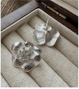 Detail of S925 sterling silver flower earrings with brushed texture and zircon center