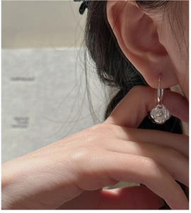 Détail macro de boucles d'oreilles créoles en argent S925 avec pendentif camélia mat