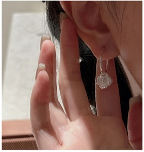 Gros plan détaillé de boucles d'oreilles fleur en argent S925 portées à l'oreille