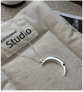 Detail of matte silver crescent moon pendant with black zircon on minimalist chain