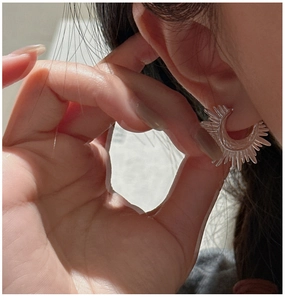 Close-up of S925 sterling silver fan-shaped earring with sunray texture on model