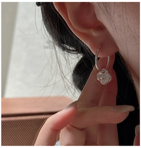 Gros plan d'une boucle d'oreille créole en argent S925 avec pendentif fleur de camélia
