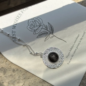 S925 sterling silver necklace featuring a textured round obsidian pendant on a gift card
