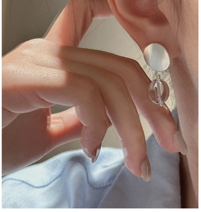 Detail view of a minimalist matte silver hoop earring with clear bead drop on a model
