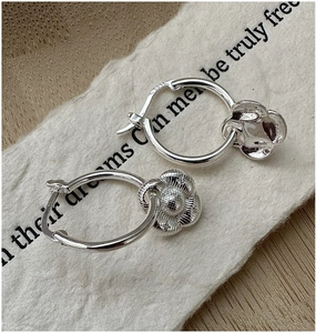 Gros plan sur des boucles d'oreilles fleur en argent S925 avec texture détaillée