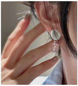 Detail of matte S925 sterling silver earrings with transparent glass bead on model