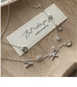 Macro detail of S925 silver LUCK necklace with letter pendants and zircons on wood