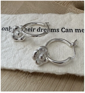 Vue macro de boucles d'oreilles créoles en argent S925 avec pétales de fleurs texturés