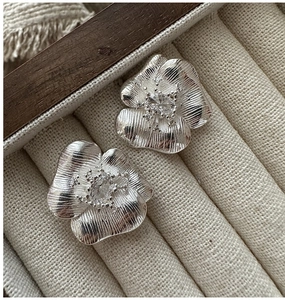 Close-up of S925 sterling silver floral earrings with brushed texture and zircon centers