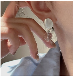Close-up of minimalist S925 sterling silver stud earring with a clear spherical drop pendant